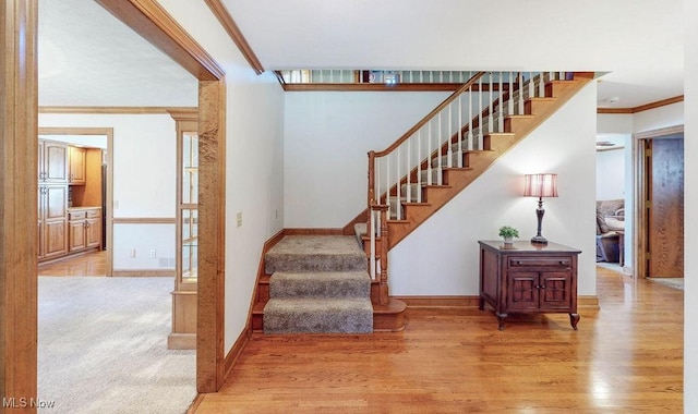 staircase with ornamental molding, baseboards, and wood finished floors
