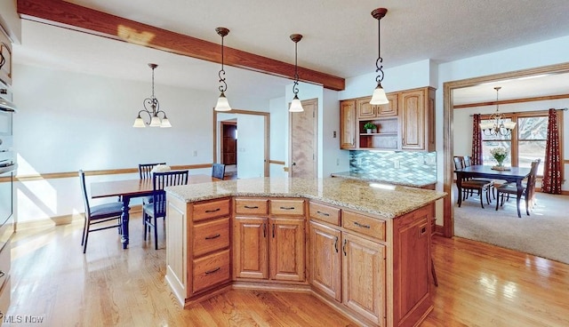 kitchen featuring light stone countertops, beam ceiling, light wood-style floors, decorative light fixtures, and a notable chandelier