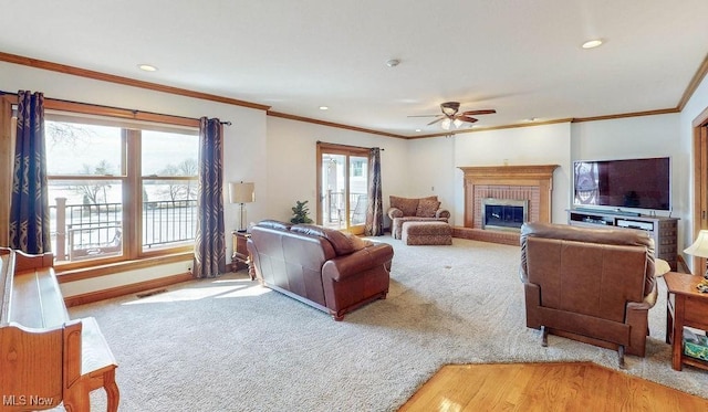 carpeted living room with baseboards, recessed lighting, ceiling fan, crown molding, and a brick fireplace
