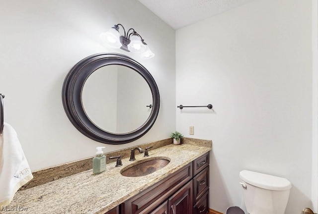 half bath with vanity, toilet, and a textured ceiling