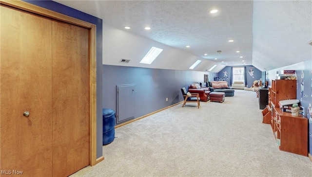 interior space featuring carpet, visible vents, baseboards, vaulted ceiling, and a textured ceiling