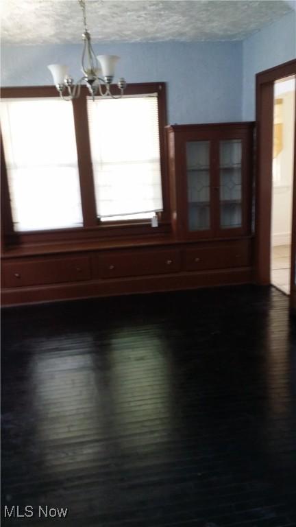 13605 Kelso Ave, Cleveland, OH 44110 - empty room featuring dark wood-style floors, a textured ceiling, and an inviting chandelier
