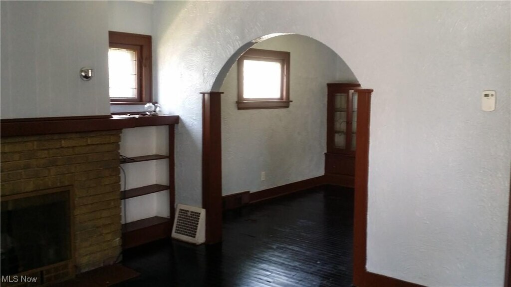 13605 Kelso Ave, Cleveland, OH 44110 - hallway featuring visible vents, arched walkways, baseboards, and wood finished floors