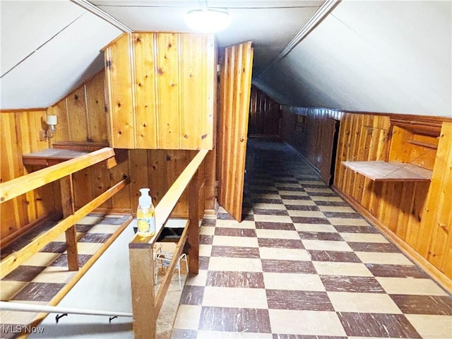bonus room with tile patterned floors, vaulted ceiling, and wood walls