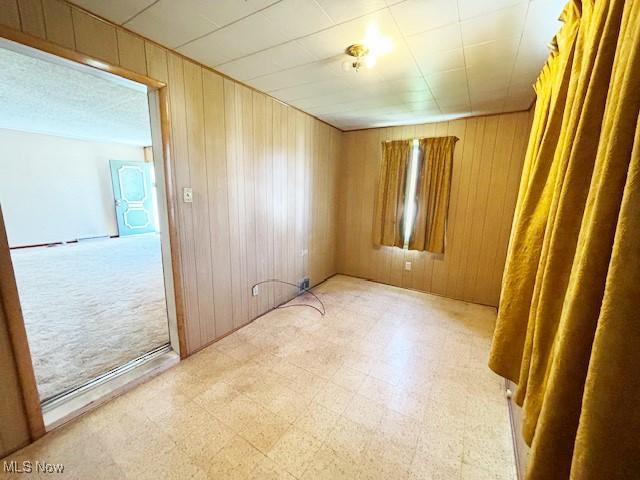 spare room featuring light floors and wood walls