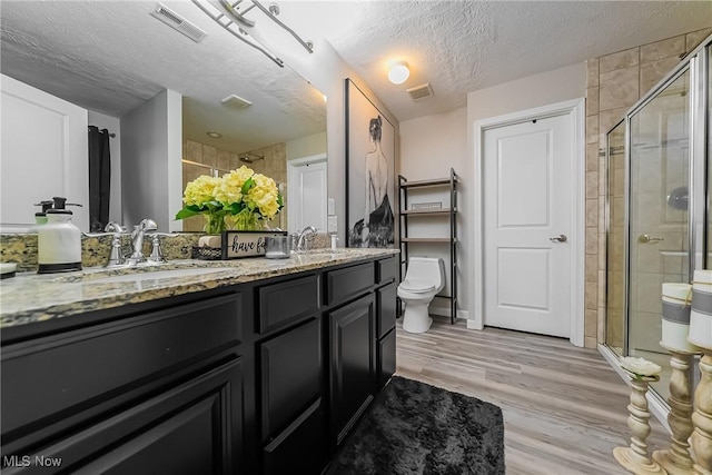 784 Hilliary Ln, Aurora, OH 44202 - full bathroom featuring a textured ceiling, a stall shower, double vanity, wood finished floors, and toilet