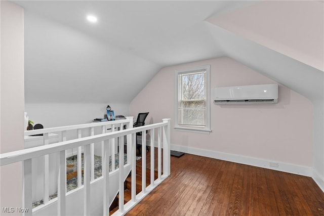 interior space with hardwood / wood-style floors, a wall mounted AC, lofted ceiling, and baseboards