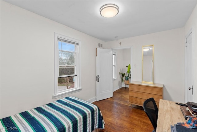 bedroom featuring visible vents, baseboards, and wood finished floors