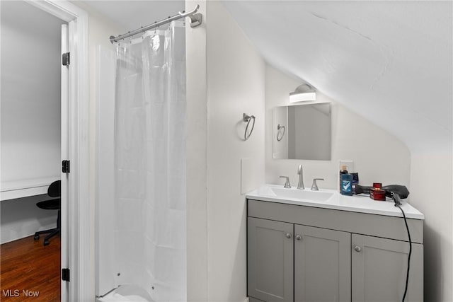bathroom featuring vanity, wood finished floors, vaulted ceiling, and curtained shower