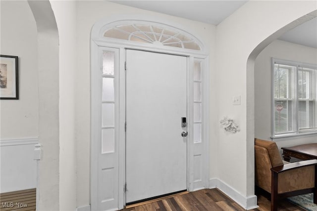 entrance foyer featuring dark wood finished floors, baseboards, and arched walkways