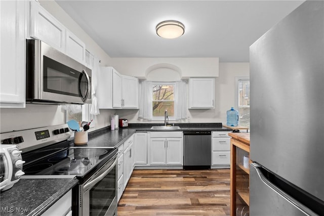 kitchen featuring white cabinets, a sink, appliances with stainless steel finishes, and wood finished floors