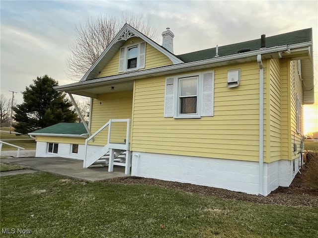 rear view of house featuring a yard, a chimney, and a patio