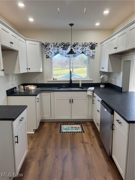 kitchen with stainless steel dishwasher, dark countertops, dark wood finished floors, and a sink