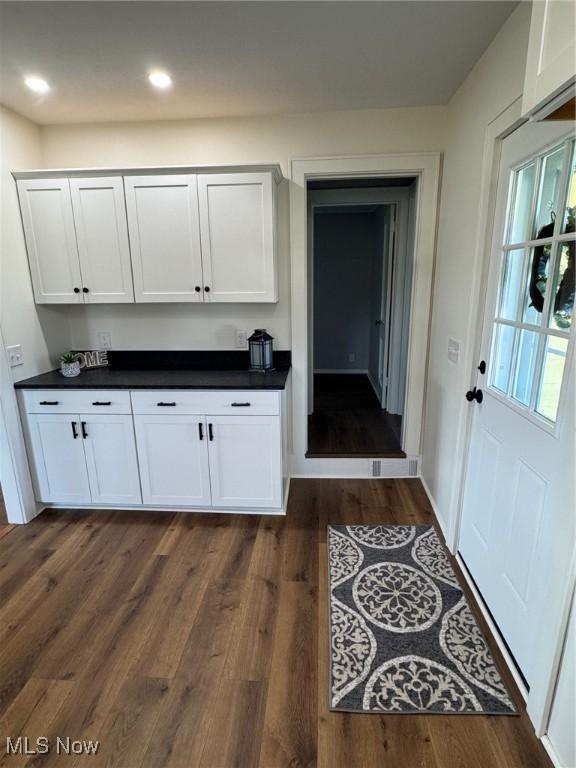 kitchen with dark wood finished floors, dark countertops, white cabinets, and recessed lighting