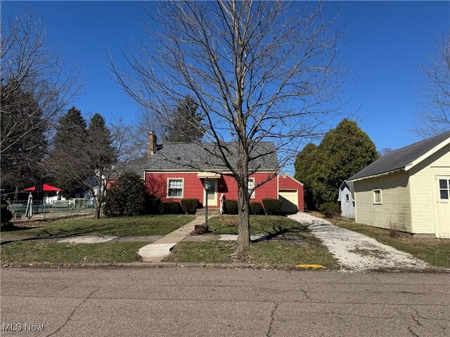 bungalow-style home featuring an outbuilding, dirt driveway, fence, a front yard, and a garage