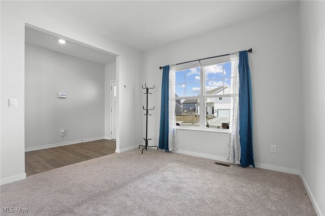 carpeted spare room with visible vents and baseboards