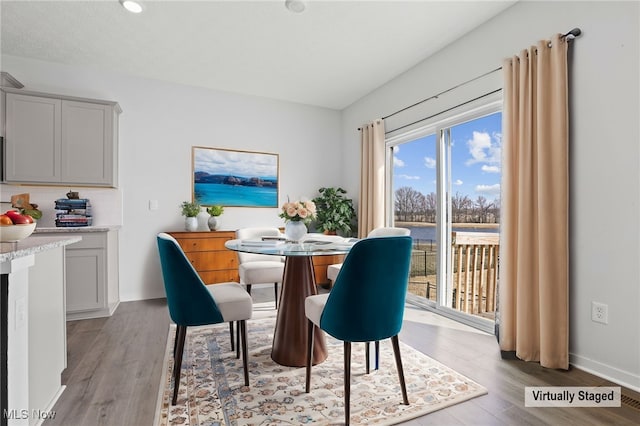 dining space featuring baseboards and light wood finished floors