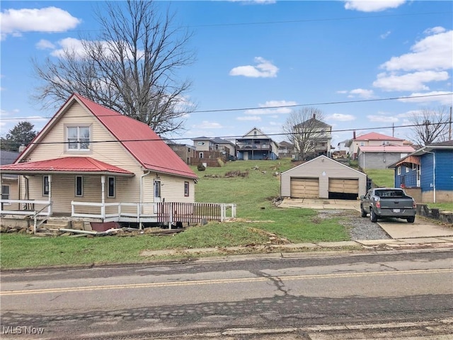 view of front facade featuring a porch, a front yard, metal roof, an outdoor structure, and a garage