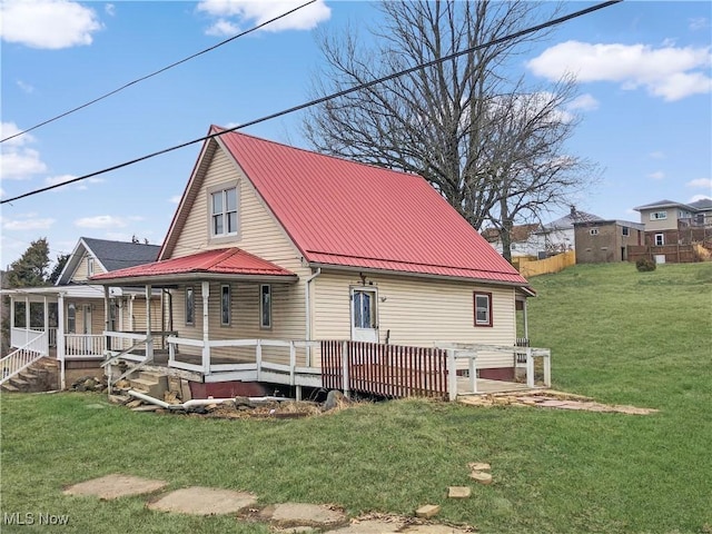 back of house with metal roof and a lawn