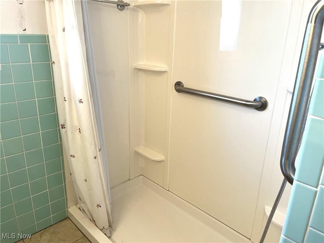 bathroom with tile patterned flooring, tile walls, and a shower stall