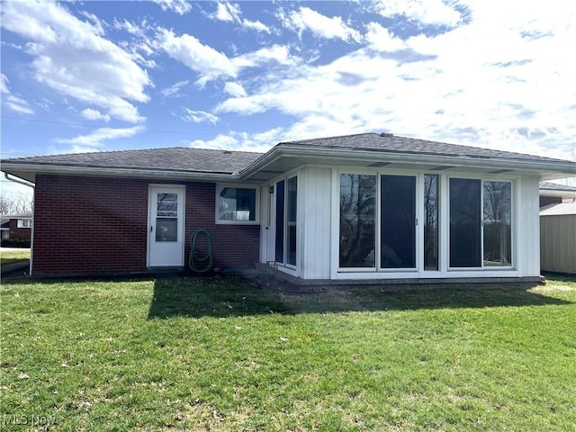 back of property with a lawn, brick siding, and a shingled roof