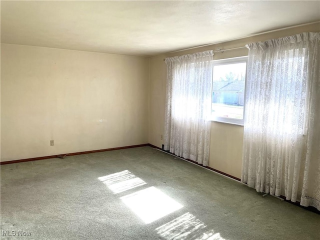 carpeted empty room featuring baseboards