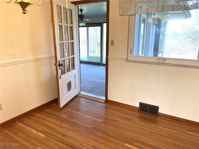 empty room featuring baseboards, wood finished floors, visible vents, and ceiling fan