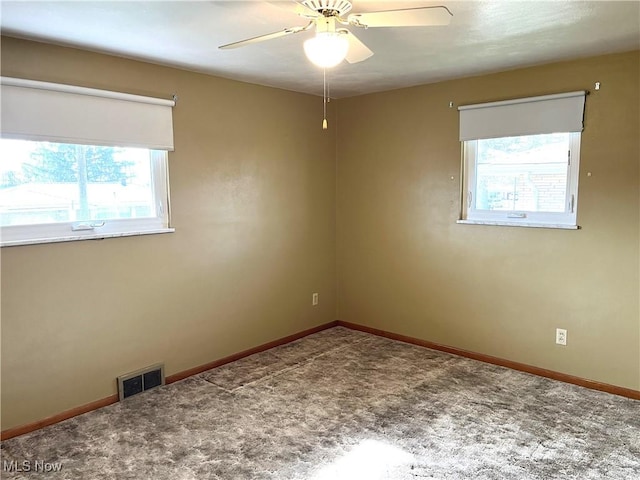 empty room featuring visible vents, a healthy amount of sunlight, and carpet flooring