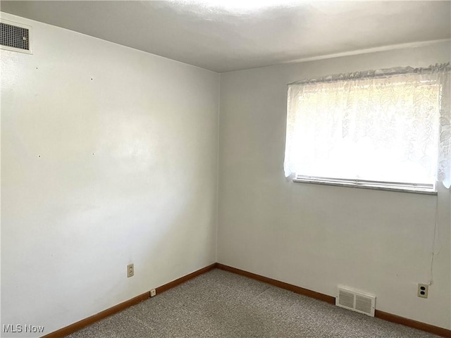 empty room with visible vents, baseboards, and carpet