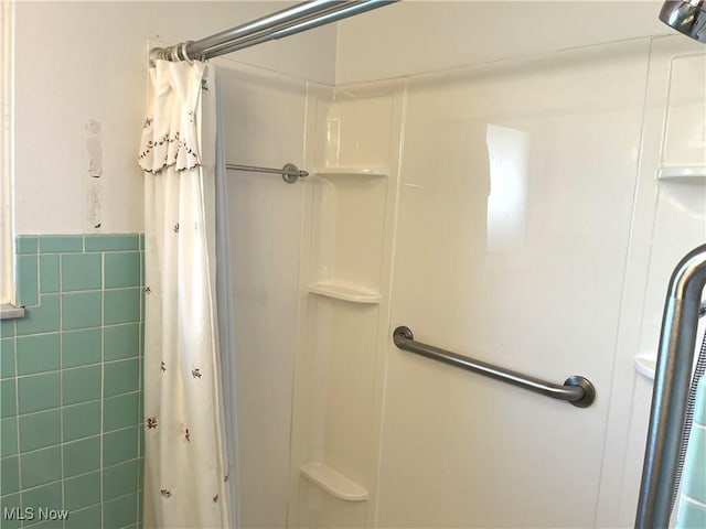 full bathroom with curtained shower, tile walls, and a wainscoted wall