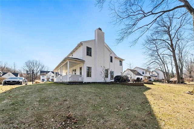 view of side of home featuring a yard, covered porch, and a chimney