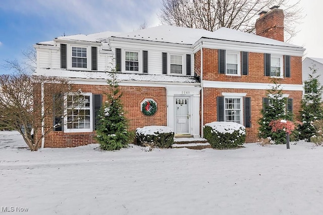 view of front of home featuring brick siding and a chimney