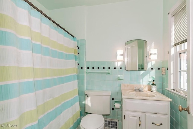 bathroom featuring visible vents, toilet, tile walls, and vanity