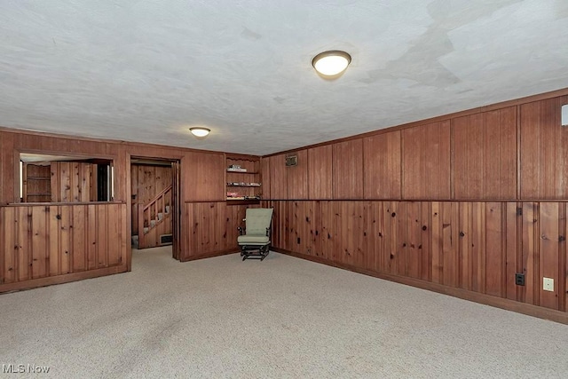 unfurnished room with wooden walls, carpet flooring, and a textured ceiling