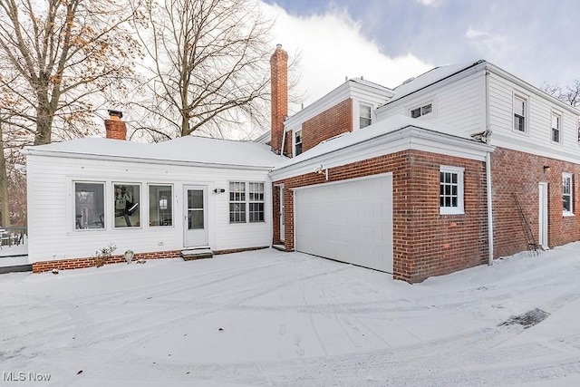 view of front of property featuring brick siding, a garage, and a chimney