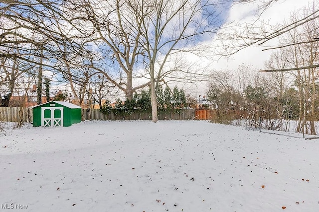 yard covered in snow with a storage unit, an outbuilding, and a fenced backyard