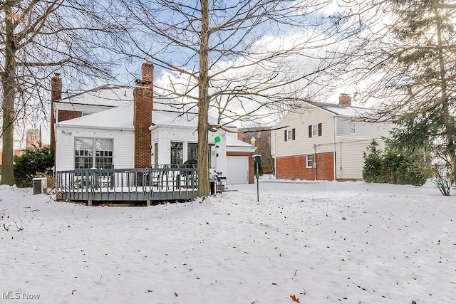 snow covered property with an outbuilding, a deck, and a chimney
