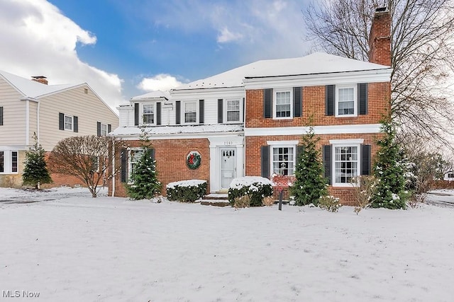 view of front of house featuring brick siding and a chimney
