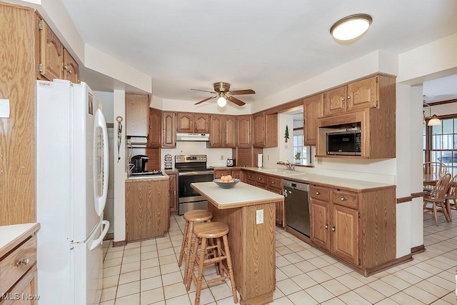 kitchen featuring light countertops, a kitchen bar, light tile patterned floors, appliances with stainless steel finishes, and a sink