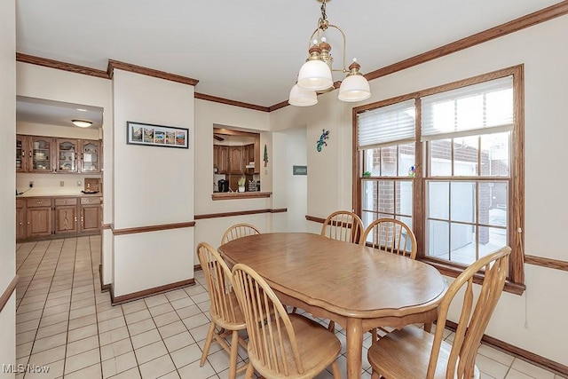 dining area with an inviting chandelier, crown molding, light tile patterned floors, and baseboards