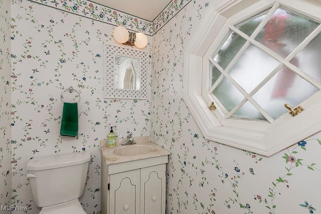 bathroom featuring vanity, toilet, and wallpapered walls