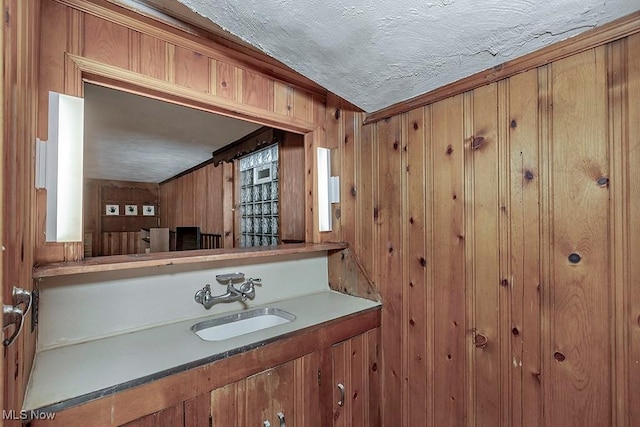 bathroom featuring vanity, wood walls, and a textured ceiling