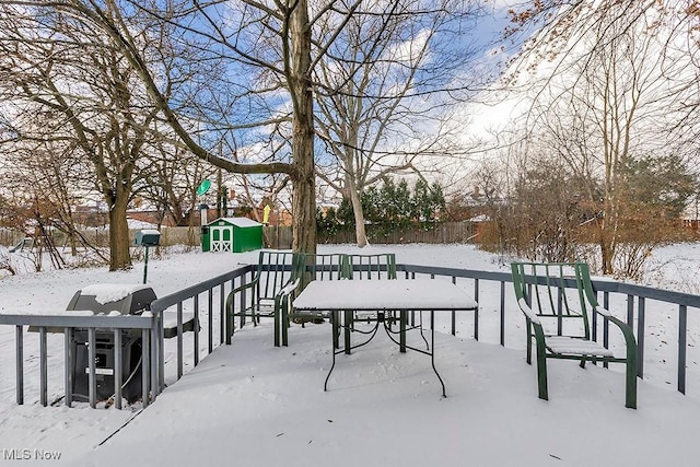 snowy yard featuring a storage shed, an outdoor structure, and fence