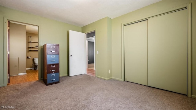 unfurnished bedroom with a closet, carpet flooring, connected bathroom, and baseboards