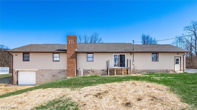 rear view of property with a lawn, cooling unit, roof with shingles, a garage, and a chimney