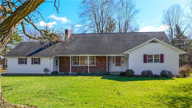 single story home featuring brick siding, a chimney, a front yard, and roof with shingles