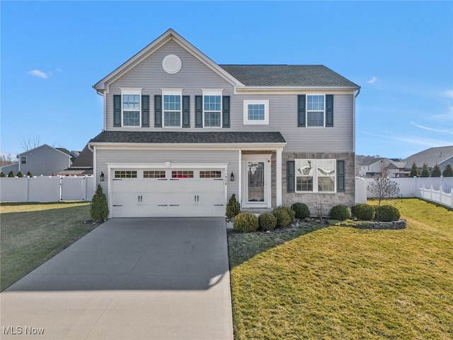 traditional-style house with fence, driveway, a front lawn, stone siding, and a garage
