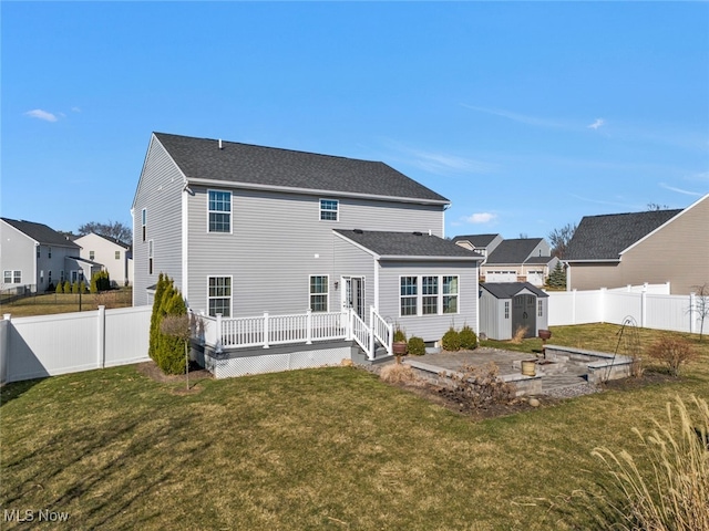 back of house with a lawn, a wooden deck, and a storage shed