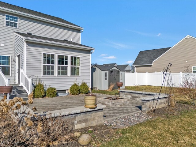 back of house with a patio, an outbuilding, fence, an outdoor fire pit, and a storage shed
