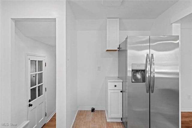 kitchen featuring light wood-style flooring, baseboards, white cabinetry, and stainless steel refrigerator with ice dispenser